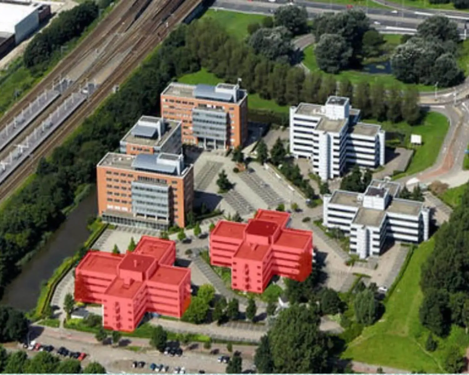Luchtfoto van een kantoorgebouwcomplex met twee rood gemarkeerde gebouwen in het midden op de voorgrond.