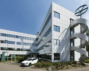 Modern kantoorpand met witte gevelpanelen, grote ramen en een opvallende buitentrap in spiraalvorm.