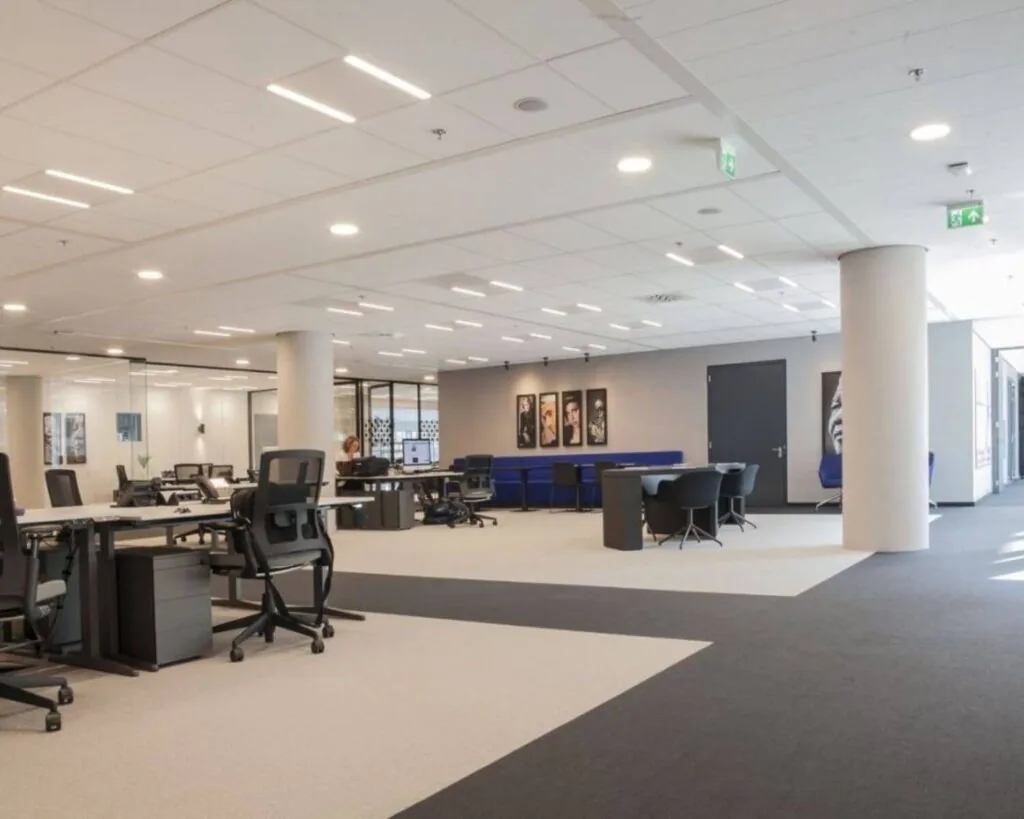 Moderne, open kantoorruimte met bureaus, bureaustoelen, vergadertafels en kunst aan de muur.