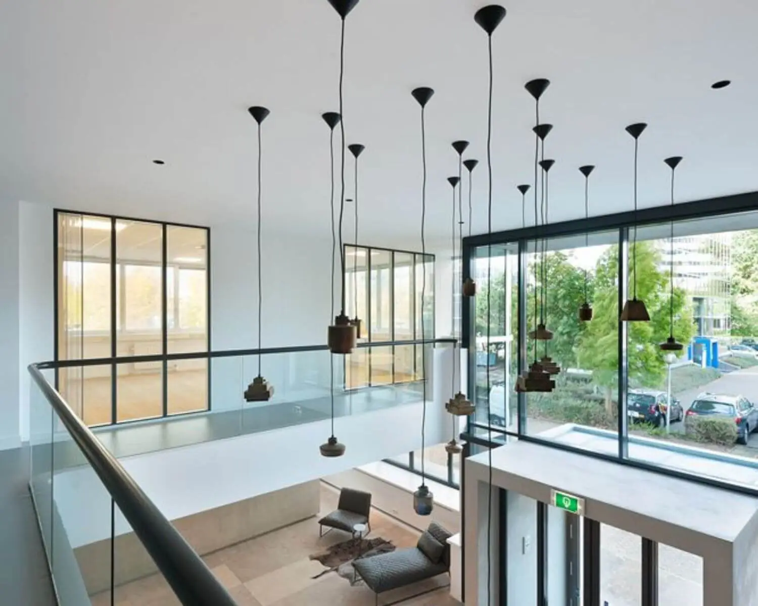 Moderne kantoorruimte met grote ramen, hanglampen en een minimalistisch interieur.