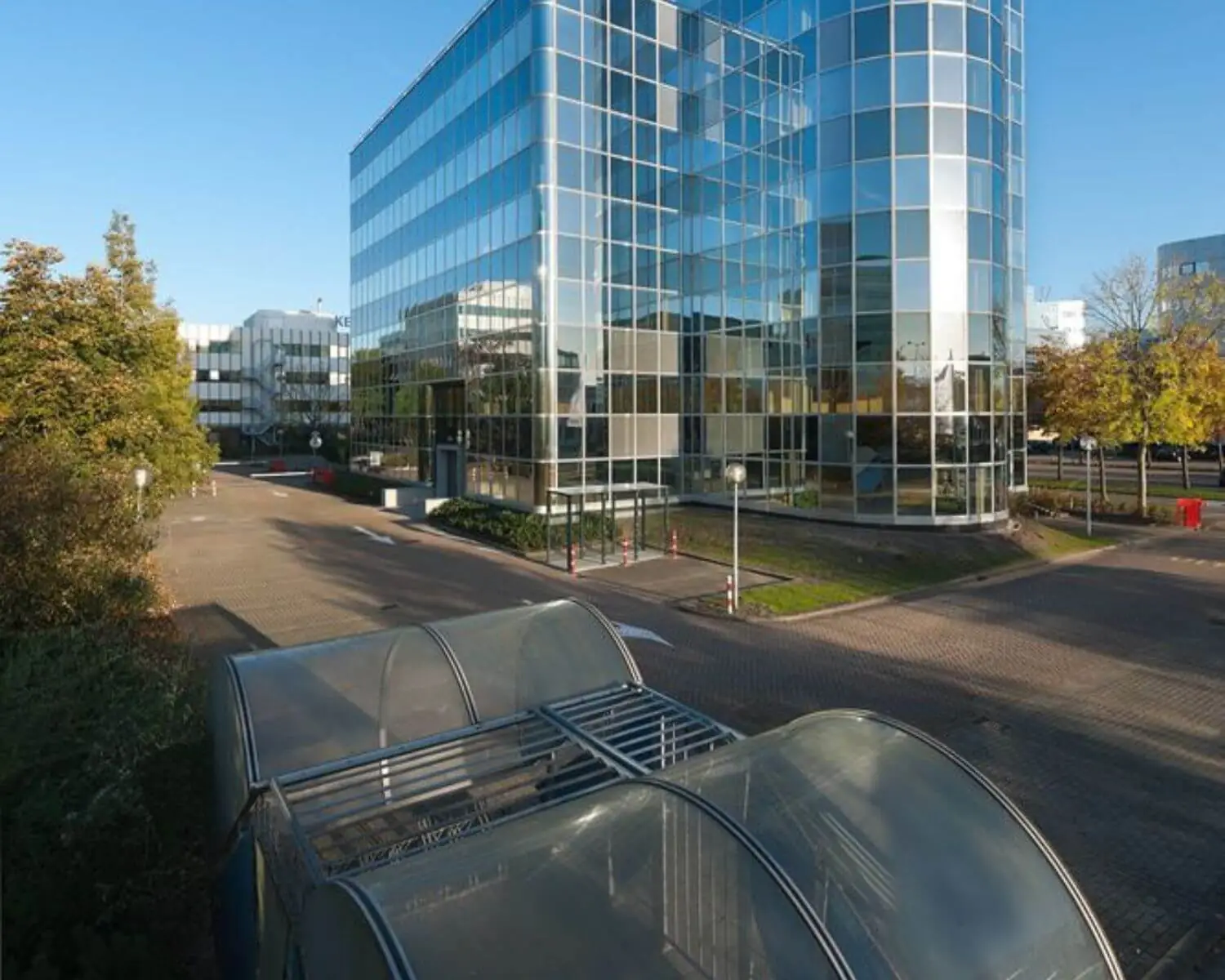 Modern kantoorgebouw met veel glasgevels en een fietsenstalling op de voorgrond.