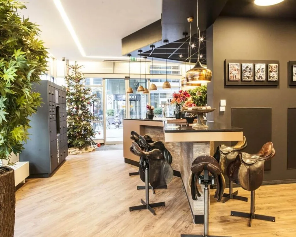 Moderne ontvangstruimte met een bar en barkrukken van zadels, een kerstboom en warme verlichting.