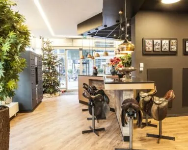 Moderne ontvangstruimte met een bar en barkrukken van zadels, een kerstboom en warme verlichting.