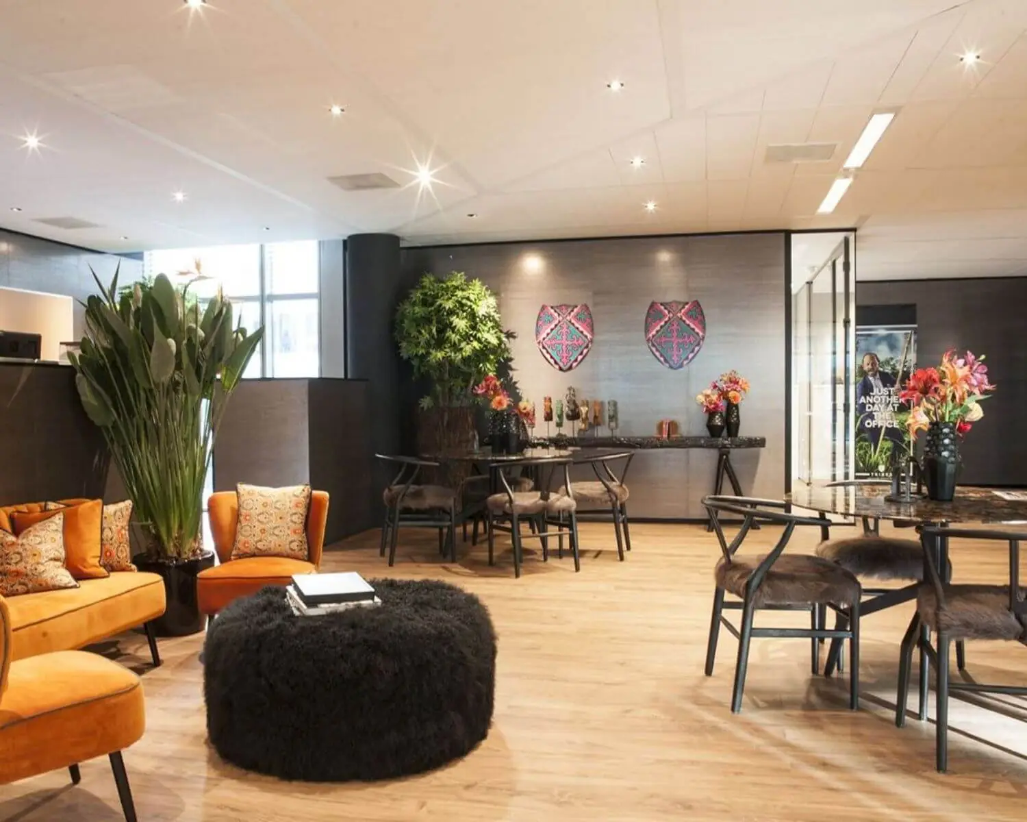 Stijlvol ingerichte lounge met oranje fauteuils, planten, bloemen en moderne kunst aan de muur.