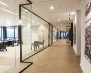 Moderne kantoorruimte met glazen vergaderruimtes en een lange gang met houten vloer.