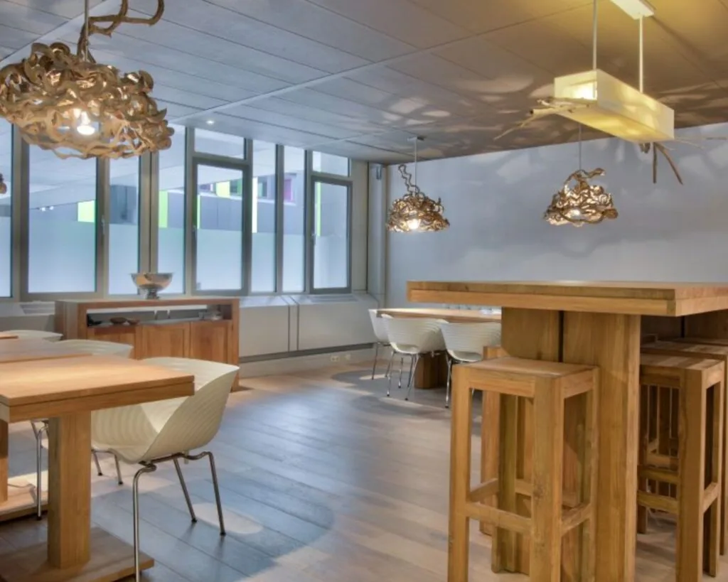 Modern ingerichte vergaderruimte met houten tafels, designstoelen en opvallende hanglampen van gevlochten hout.
