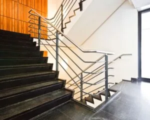 Moderne binnentrap met zwarte treden, metalen leuningen en houten wandpanelen.