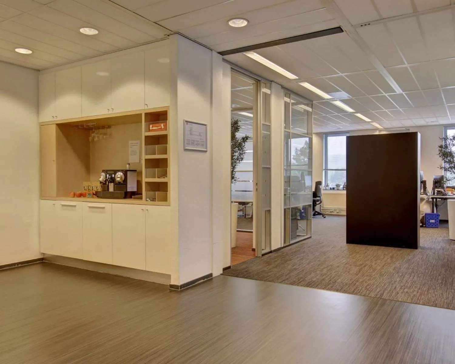 Moderne kantoorpresentatie met een koffiehoek en werkplekken op de achtergrond.