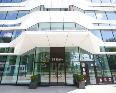 Voorgevel van het moderne kantoorgebouw van UNStudio met glazen wanden en witte architectonische elementen.