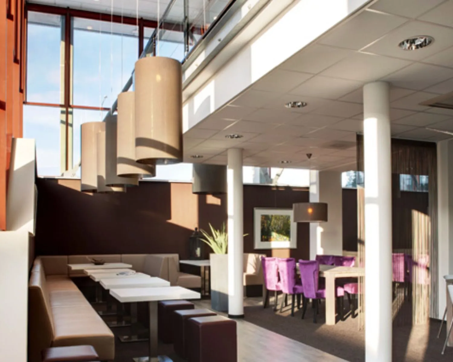 Moderne en sfeervolle zithoek in een restaurant met paarse stoelen en hanglampen.