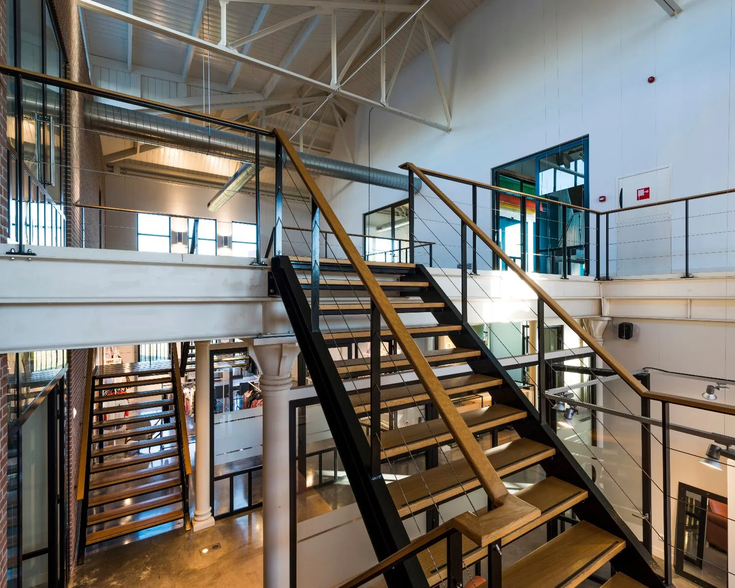 Moderne industriële kantoorruimte met open trap en glazen balustrades.