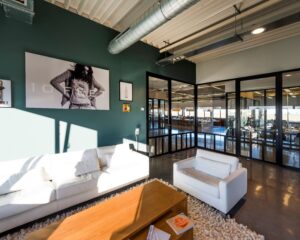 Modern ingerichte kantoorlounge met witte banken, een houten salontafel en kunst aan de muur met de tekst "10FEET".