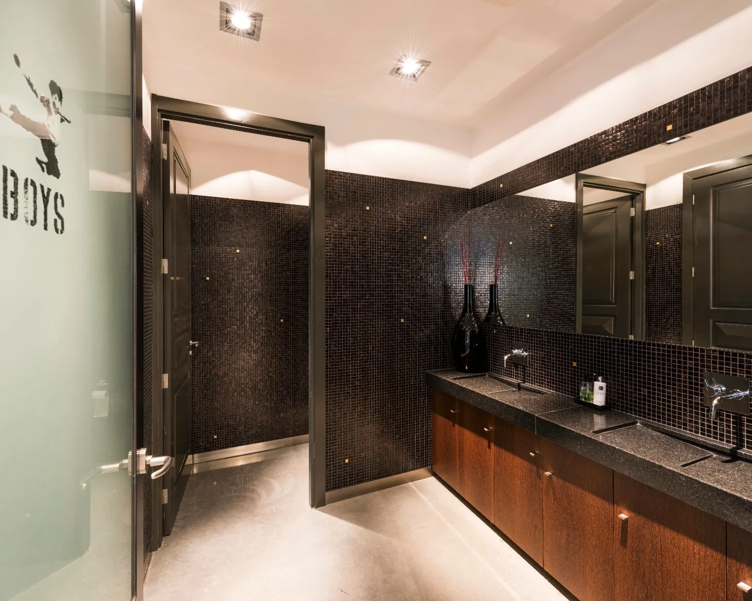 Moderne herentoilet met donkere mozaïektegels, houten wastafelmeubel en strakke afwerking.