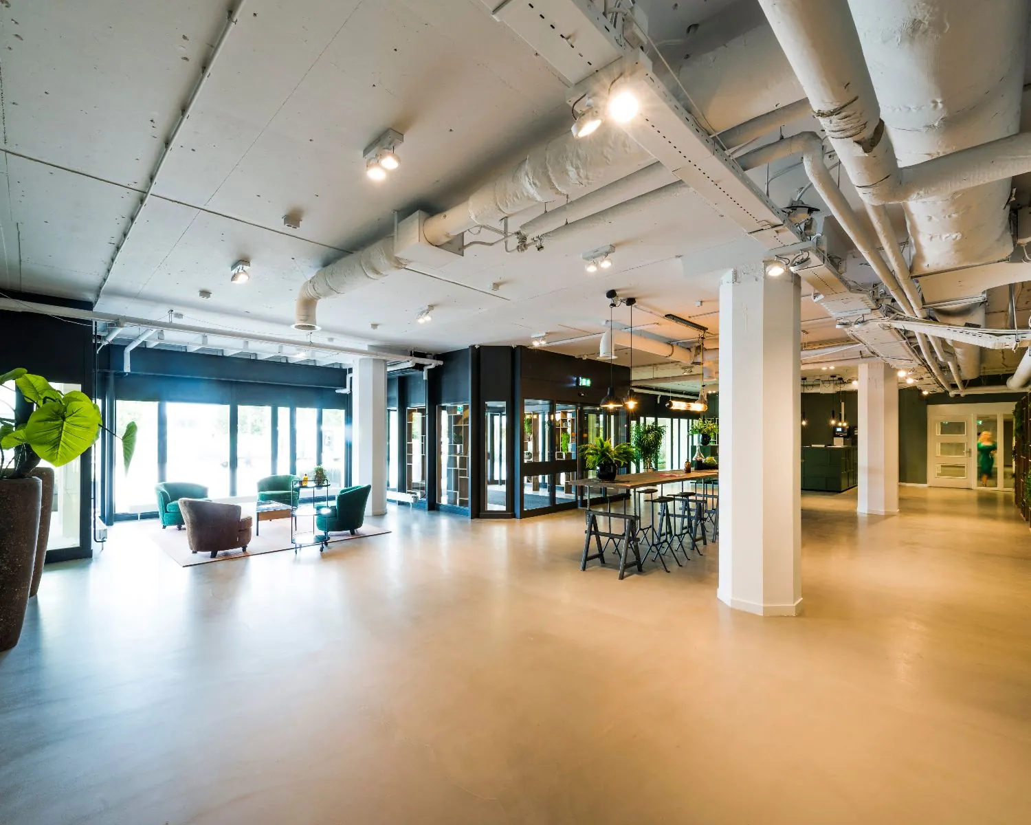 Moderne, open kantoorruimte met zitgedeelte, lange vergadertafel en veel natuurlijke lichtinval.