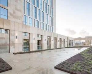 Moderne kantoor- of overheidsgebouw met glazen ramen en een betegeld plein met aangelegde borders.