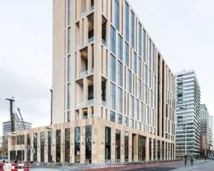 Modern beige kantoorgebouw met grote ramen in een stedelijke omgeving.