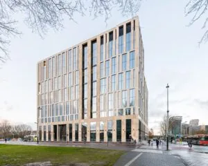 Modern kantoorgebouw met grote ramen aan een druk kruispunt in een stedelijke omgeving.