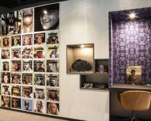 Fotowand met portretten van inheemse volkeren naast een moderne leeshoek met het boek *Before They Pass Away* van Jimmy Nelson.