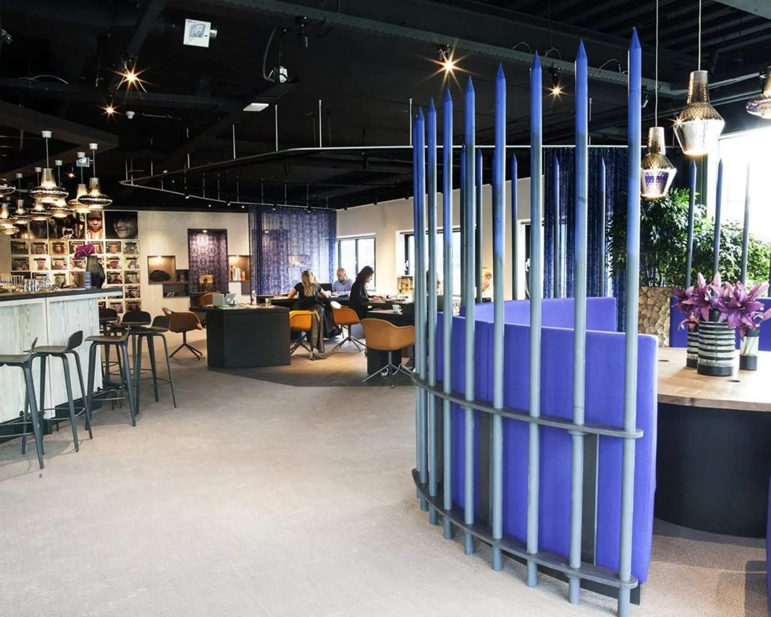 Modern ingericht kantoor met zithoeken, kunst aan de muren en een opvallend paarsblauw afscheidingsobject.