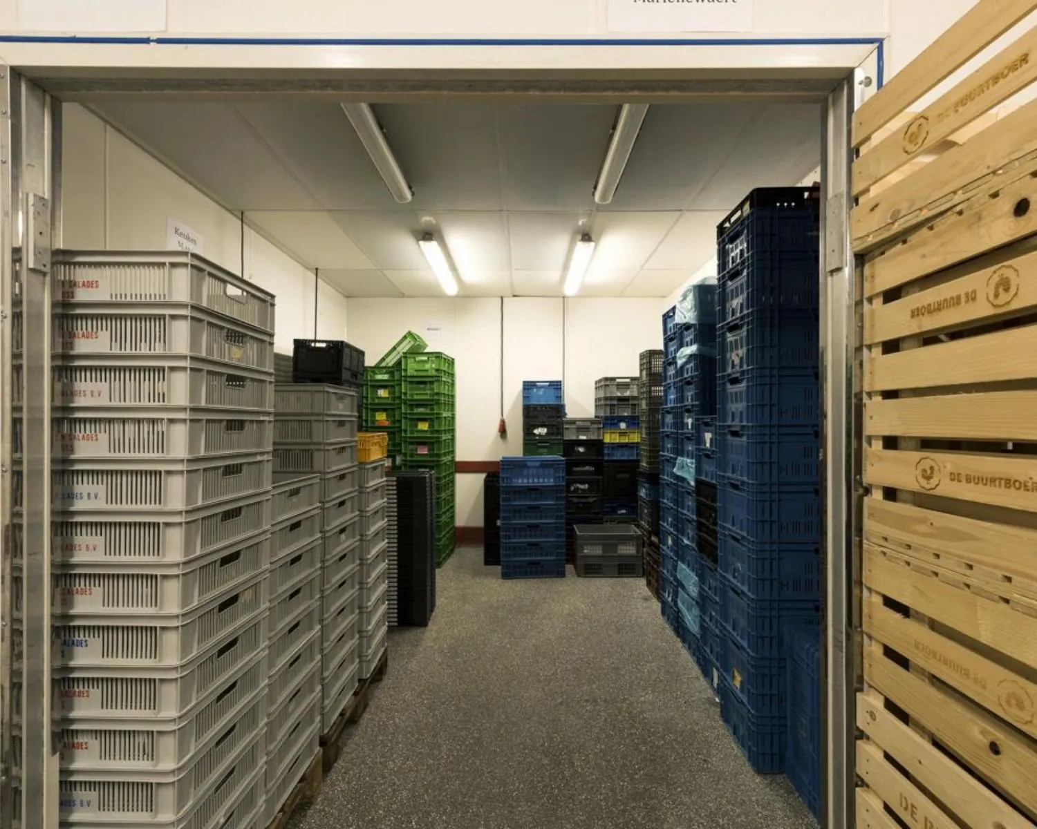 Opslagruimte met gestapelde kunststof en houten kratten van De Buurtboer en andere leveranciers.