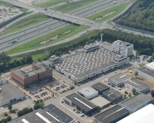 Luchtfoto van een bedrijventerrein nabij een knooppunt van snelwegen met kantoren, magazijnen en parkeerplaatsen.