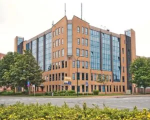 Kantoorgebouw met gevels van roodbruin metselwerk en grote raampartijen aan een kruispunt.