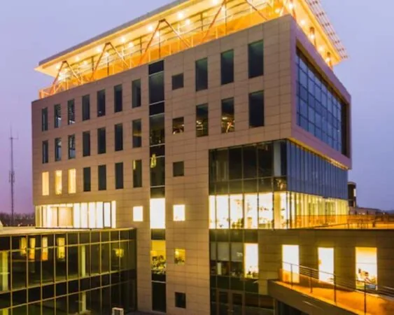 Verlicht kantoorgebouw bij schemering met moderne architectuur en glazen gevel.