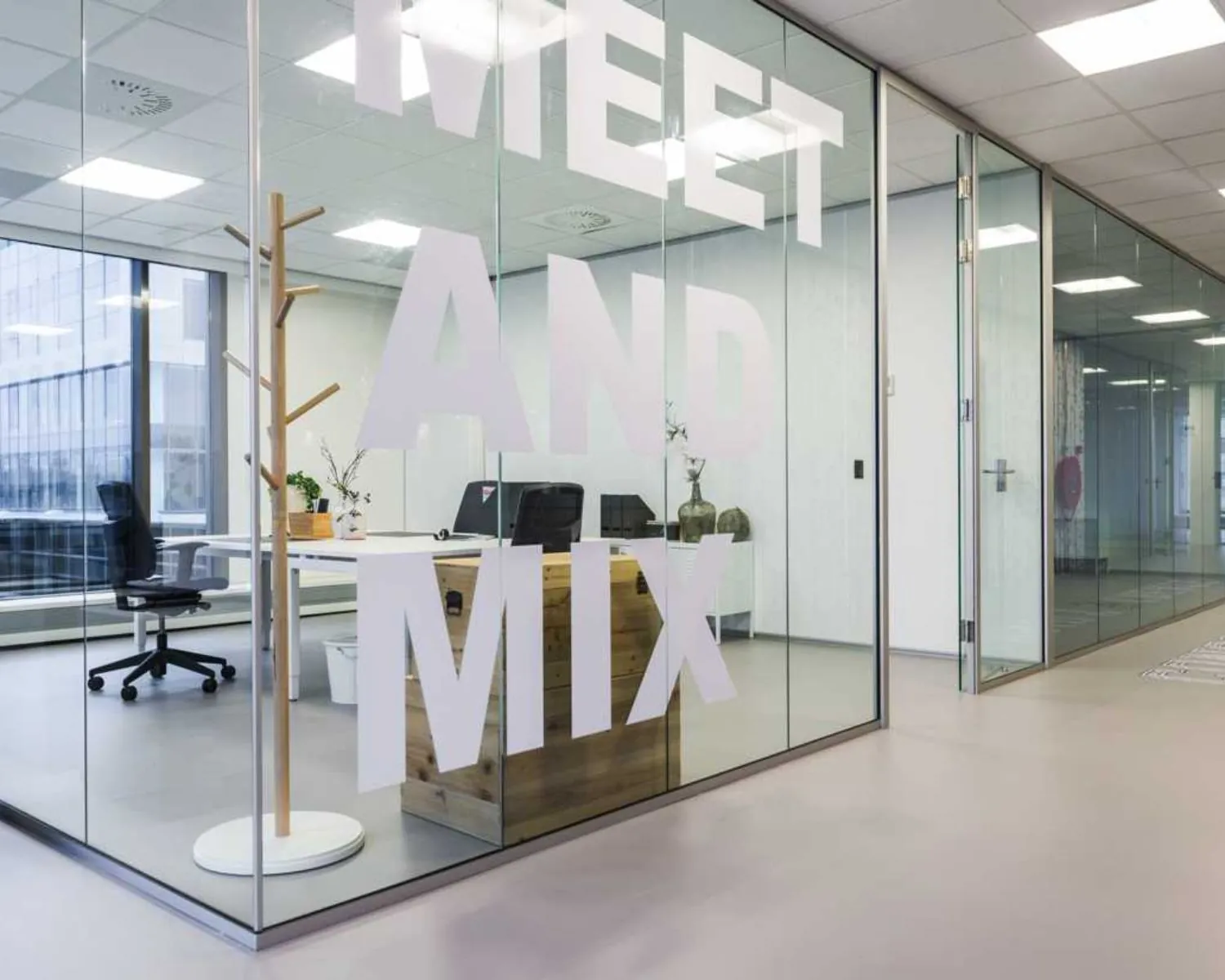 Moderne vergaderruimte met glazen wanden waarop de tekst "MEET AND MIX" staat.