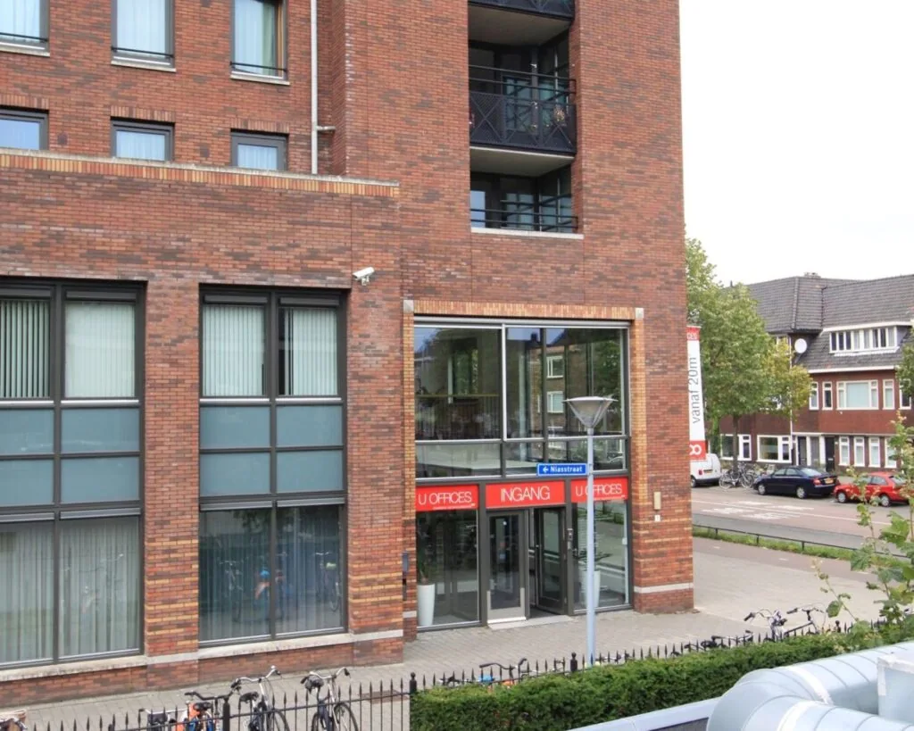 Hoofdingang van het U Offices kantoorgebouw aan de Niasstraat, met fietsenrekken op de voorgrond.