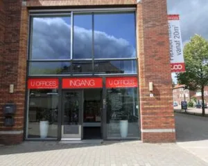 Ingang van U Offices in een modern rood-bruin bakstenen gebouw met grote ramen.