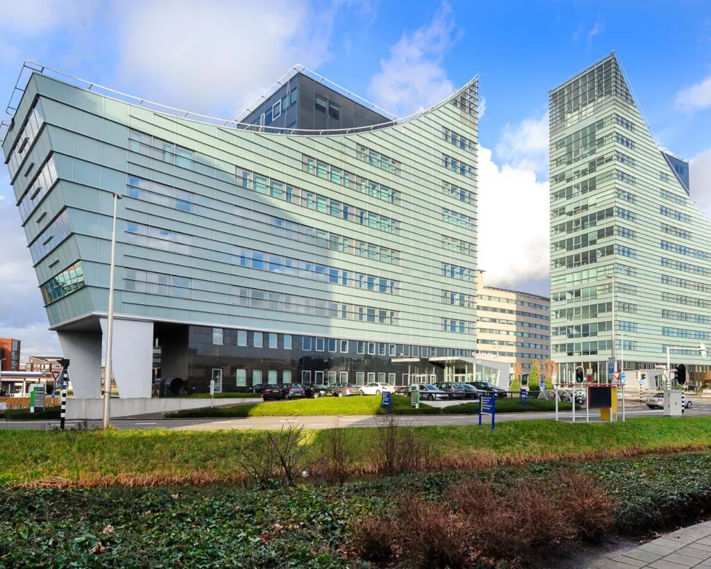 Twee moderne kantoorgebouwen met glazen gevels in een stedelijke omgeving.