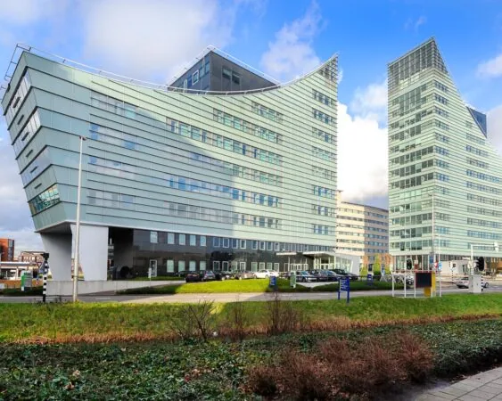 Twee moderne kantoorgebouwen met glazen gevels in een stedelijke omgeving.