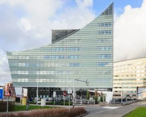 Modern kantoorgebouw met schuine glazen gevel, genaamd Crystal Building A, gelegen aan een rotonde.