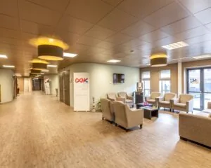 Moderne wachtruimte met comfortabele stoelen en een banner van Stichting OK in een zorginstelling.