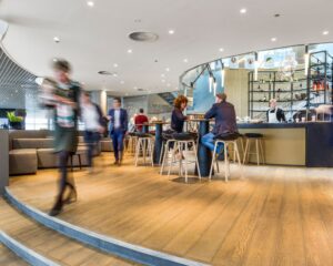 Moderne, drukke koffielounge met mensen die aan tafels zitten en rondlopen.