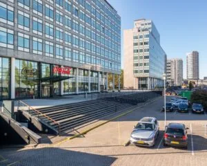 Kantoorgebouw met Coca-Cola-logo bij de ingang en parkeervakken op de voorgrond.