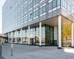 Moderne kantoorgebouw met glazen gevel en witte zuilen aan een open plein.