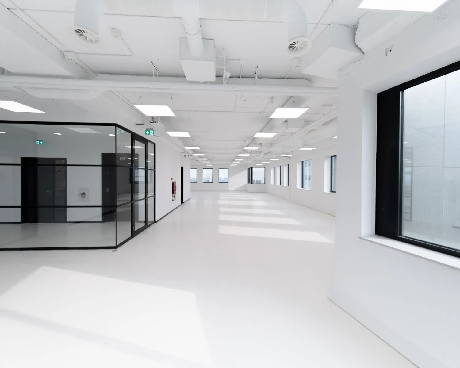 Licht en modern leeg kantoorpand met grote ramen en glazen binnenwanden.