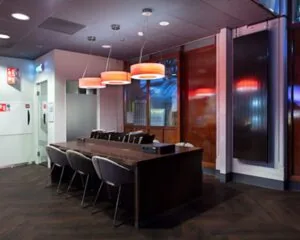 Moderne vergaderruimte met een lange tafel, comfortabele stoelen en hanglampen met rood licht.