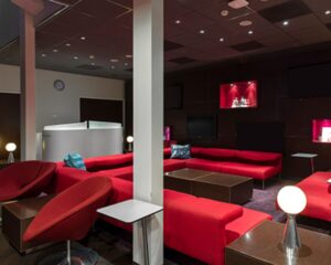 Moderne lounge met rode banken, donkere muren en sfeervolle verlichting.