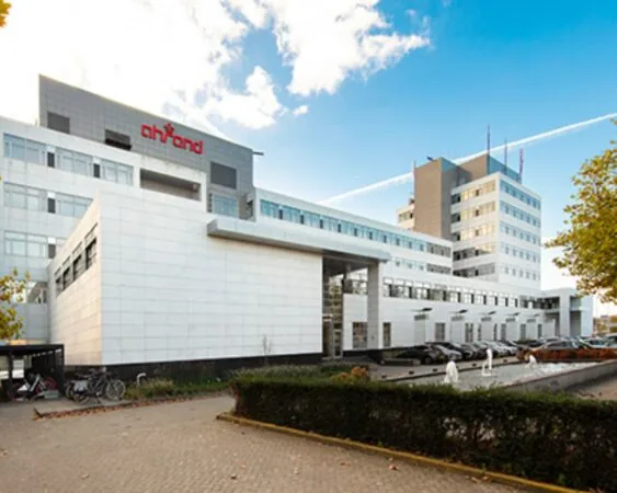 Modern kantoorgebouw van Ahrend met witte gevel en meerdere verdiepingen onder een blauwe lucht.