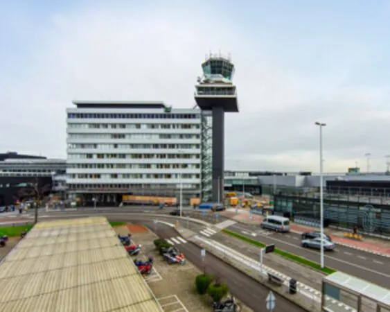 Luchtverkeerstoren en luchthavengebouwen van Schiphol gezien vanaf een naastgelegen weg.