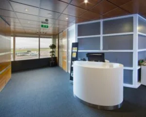 Moderne luchthavenlounge met receptiebalie en uitzicht op het vliegveld.