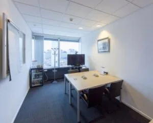 Vergaderruimte met een tafel, vier stoelen, een flatscreen-tv, flip-over en uitzicht op een zakendistrict.