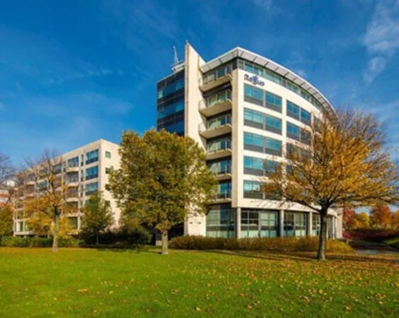 Modern kantoorgebouw van Radisson met glazen gevels, omgeven door herfstbomen en een groen grasveld.