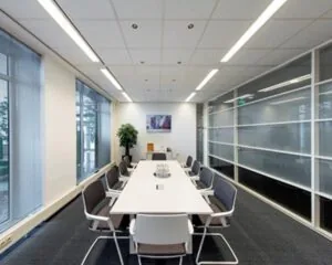 Moderne vergaderruimte met een lange tafel, tien stoelen, glazen wanden en grote ramen.