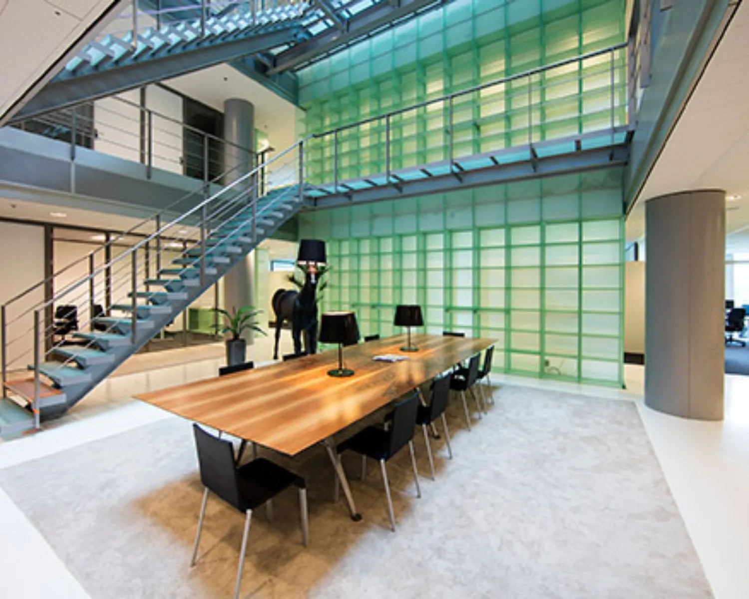 Moderne vergaderruimte met een lange houten tafel, zwarte stoelen en een opvallende glazen wand met groene accenten.