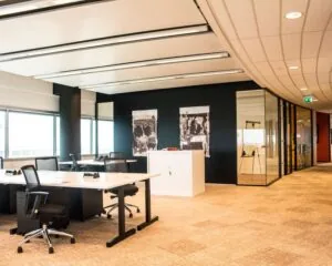 Moderne open kantoorruimte met bureaus, stoelen en glazen vergaderruimtes.