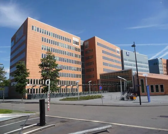 Modern kantoorgebouw met oranje en grijze gevels onder een blauwe lucht.