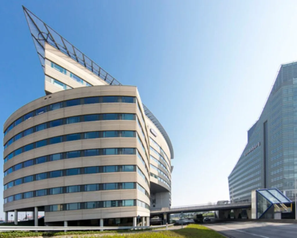 Kantoorgebouwen met moderne architectuur langs een weg onder een heldere blauwe lucht.